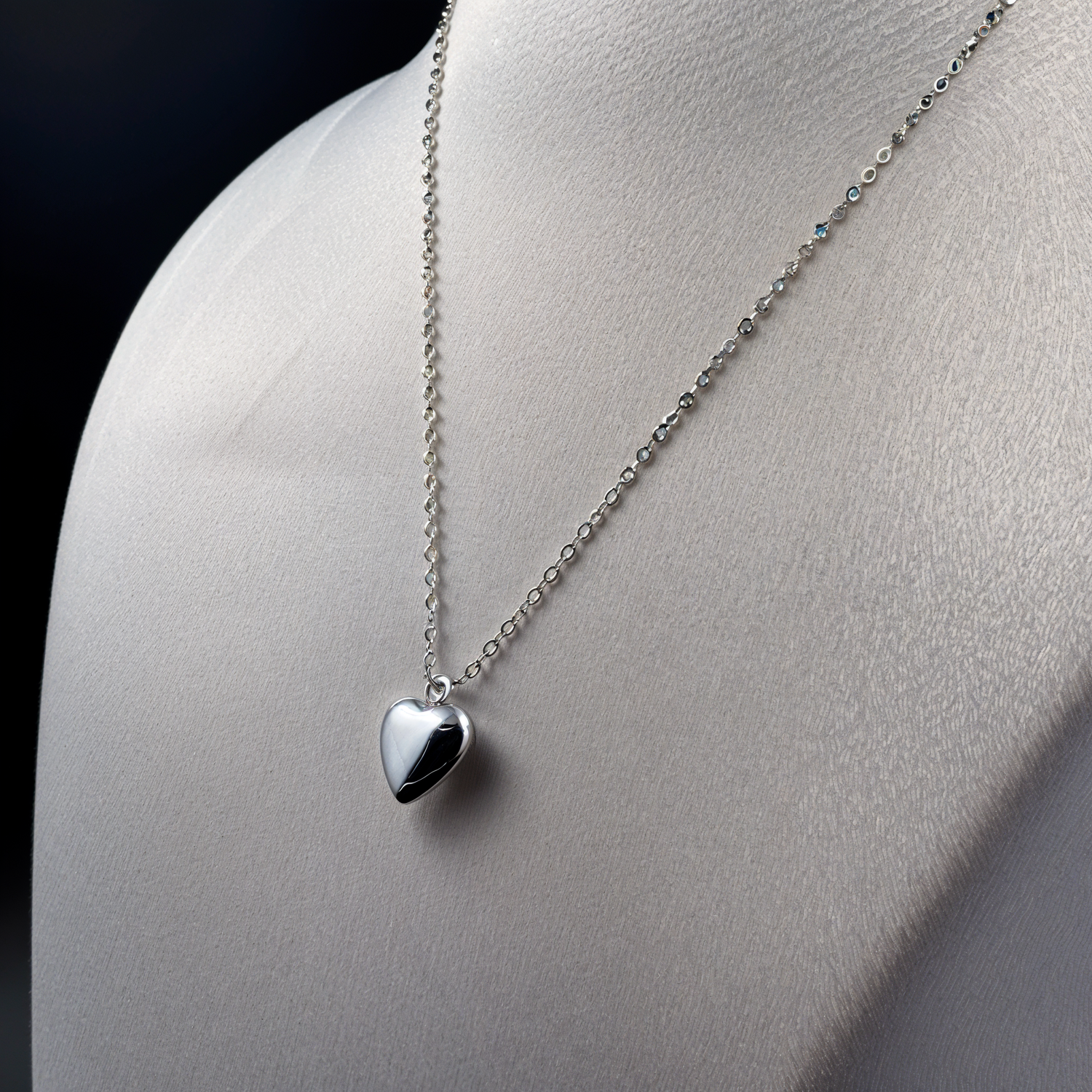 Silver heart-shaped pendant necklace on a mannequin.